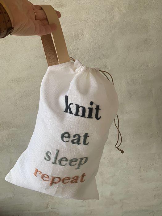 Strikkepose med broderi og teksten "Knit, eat, sleep, repeat"